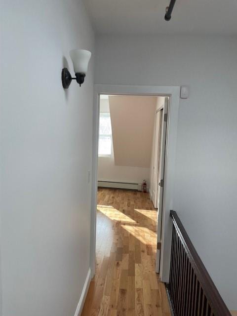 corridor with a baseboard radiator, radiator, and light wood-type flooring