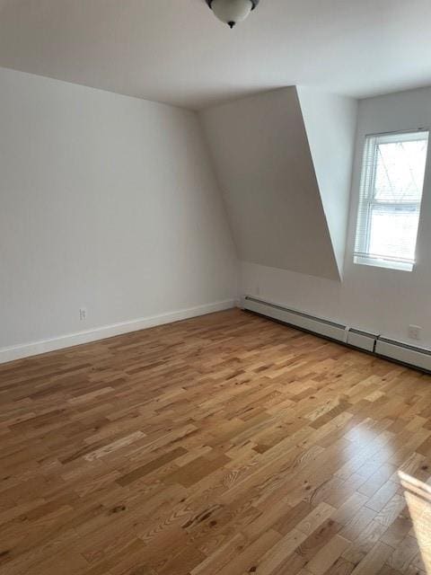 additional living space featuring baseboard heating, wood finished floors, and baseboards