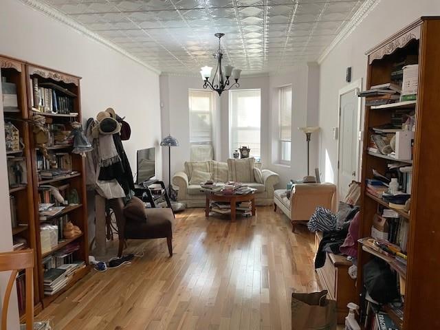 sitting room with light wood finished floors, a notable chandelier, and ornamental molding