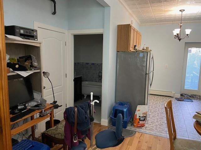 kitchen with a notable chandelier, a baseboard heating unit, freestanding refrigerator, crown molding, and wood finished floors