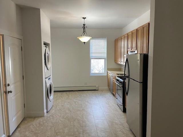 kitchen featuring brown cabinetry, stacked washer / dryer, stainless steel appliances, a baseboard radiator, and baseboards