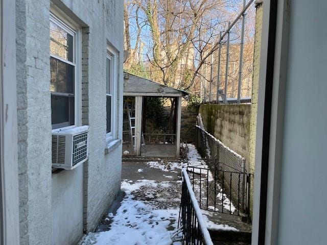 snow covered property featuring stucco siding, cooling unit, and fence