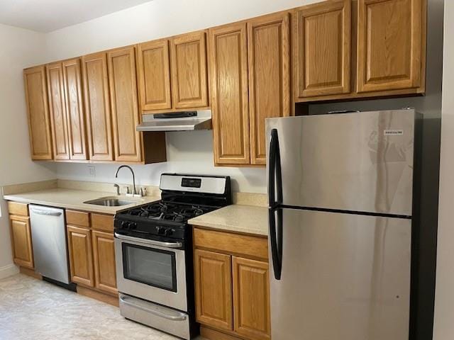 kitchen featuring a sink, light countertops, under cabinet range hood, brown cabinetry, and stainless steel appliances