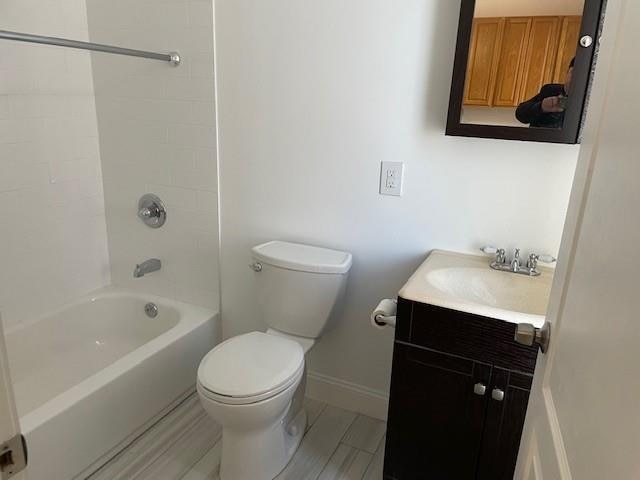 bathroom with toilet, shower / bath combination, vanity, and baseboards