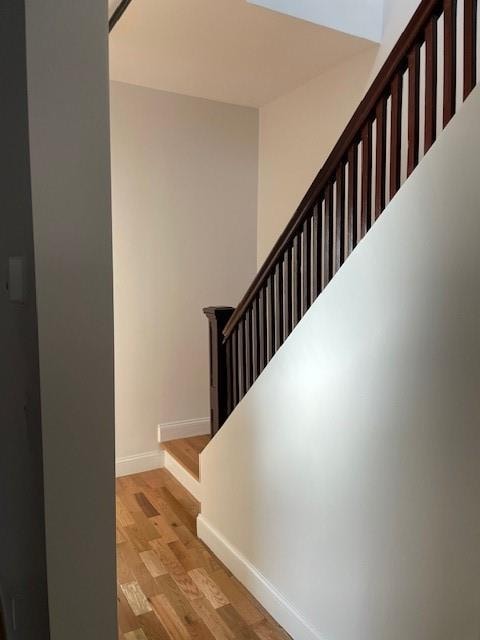 staircase with baseboards and wood finished floors