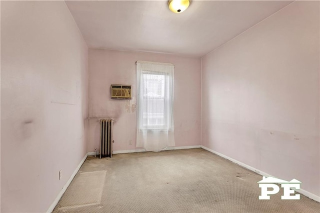 empty room featuring radiator, a wall unit AC, baseboards, and carpet flooring