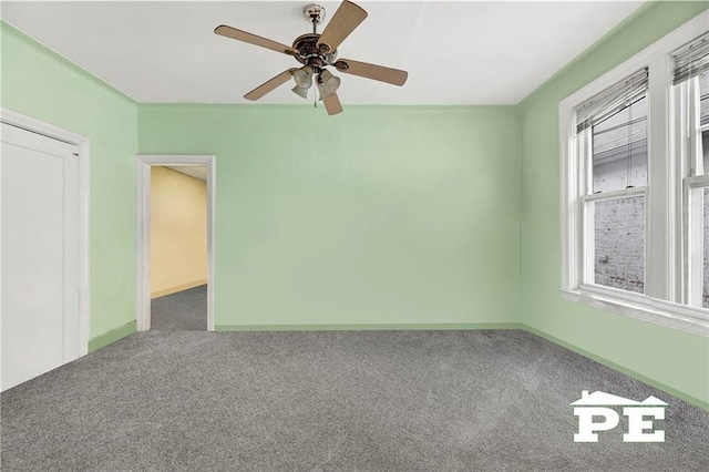 carpeted spare room featuring ceiling fan and baseboards