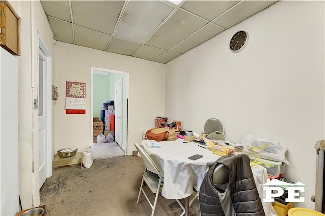 dining space featuring unfinished concrete flooring and a paneled ceiling