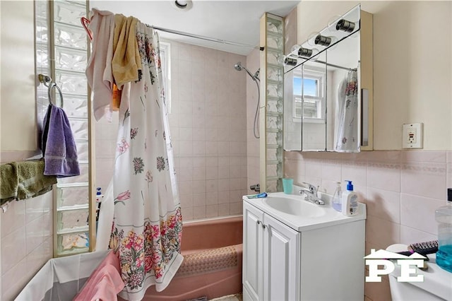 full bath with shower / tub combo, vanity, and tile walls