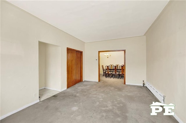 carpeted spare room featuring a baseboard radiator, baseboards, and a notable chandelier