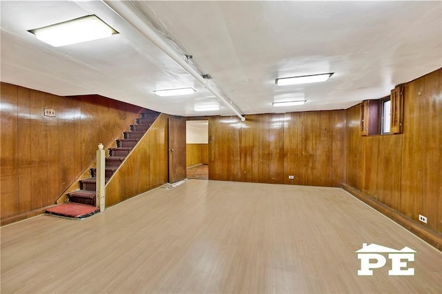 finished basement featuring stairs, wood finished floors, and wooden walls