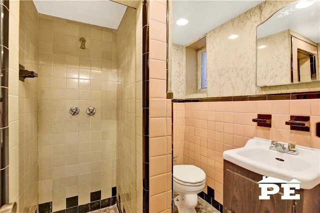 full bath with toilet, a wainscoted wall, a sink, tile walls, and a shower stall