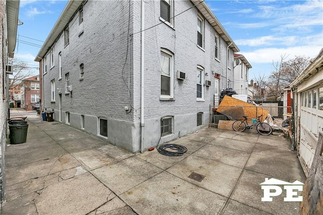 view of side of property featuring brick siding, fence, and a patio