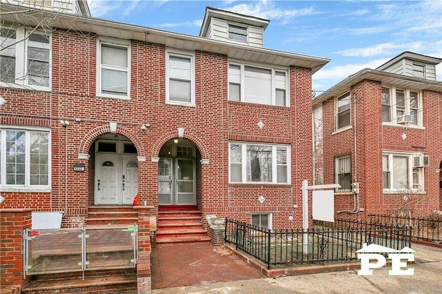 view of front facade featuring entry steps, a fenced front yard, and brick siding