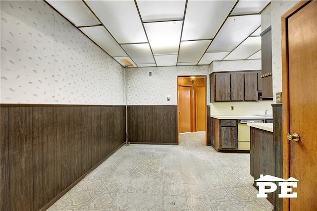 interior space featuring a wainscoted wall, wood walls, wallpapered walls, and dishwasher