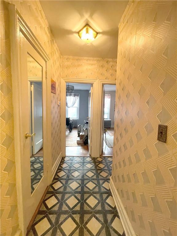 corridor featuring baseboards and wallpapered walls