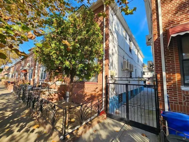 view of side of property featuring a gate and brick siding