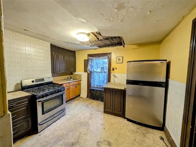 kitchen with a sink, stainless steel appliances, light countertops, and dark brown cabinetry