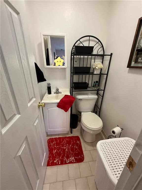 half bath featuring toilet, tile patterned flooring, and vanity