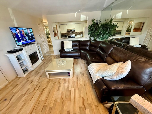 living area with light wood-type flooring and a glass covered fireplace