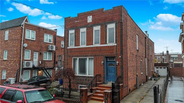 view of front facade featuring ac unit, an outbuilding, brick siding, a wall mounted AC, and driveway