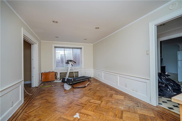 exercise room with a wainscoted wall, ornamental molding, and a decorative wall