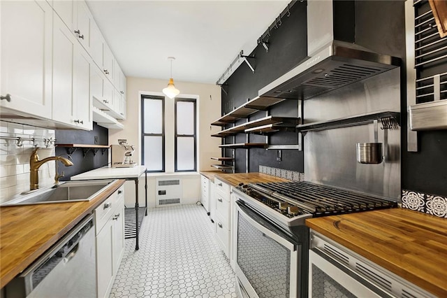 kitchen with pendant lighting, white cabinetry, wooden counters, and a sink