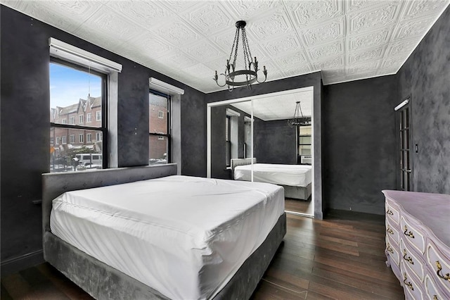 bedroom with dark wood-style floors, baseboards, an ornate ceiling, and an inviting chandelier