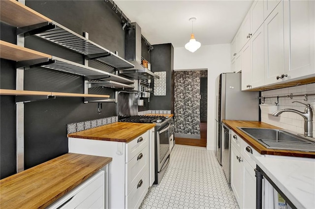 kitchen featuring open shelves, hanging light fixtures, wood counters, and stainless steel appliances