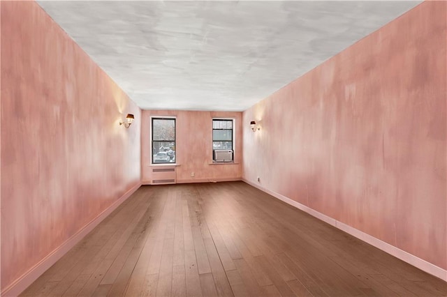 empty room with hardwood / wood-style flooring, baseboards, and cooling unit