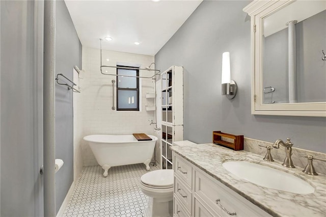 full bath with tile walls, a freestanding bath, toilet, vanity, and tile patterned floors