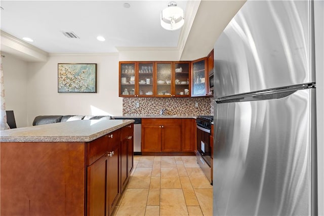 kitchen with decorative backsplash, glass insert cabinets, appliances with stainless steel finishes, hanging light fixtures, and light countertops