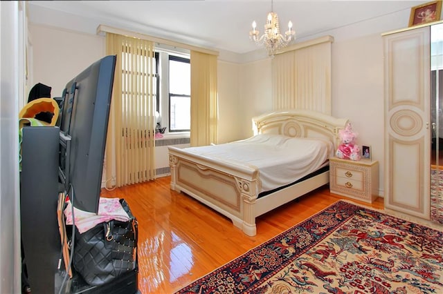 bedroom with light wood-style floors, radiator, and a chandelier