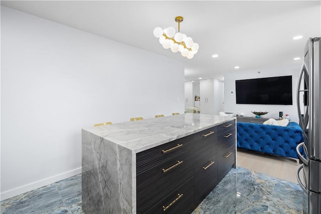 kitchen featuring baseboards, modern cabinets, freestanding refrigerator, hanging light fixtures, and dark cabinetry