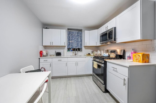 kitchen featuring stainless steel appliances, light countertops, a sink, and decorative backsplash