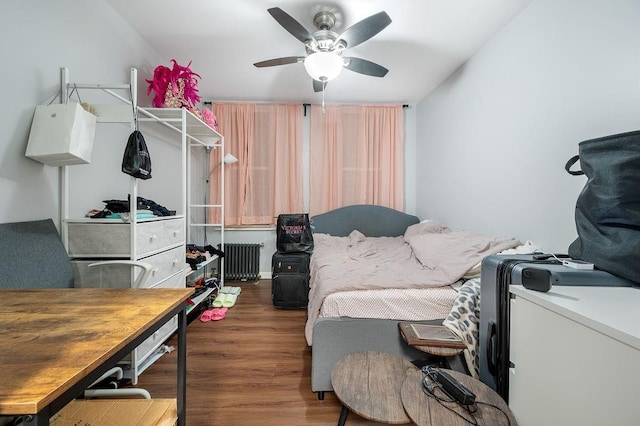 bedroom featuring radiator heating unit, a ceiling fan, and wood finished floors