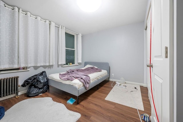 bedroom featuring radiator, baseboards, and wood finished floors