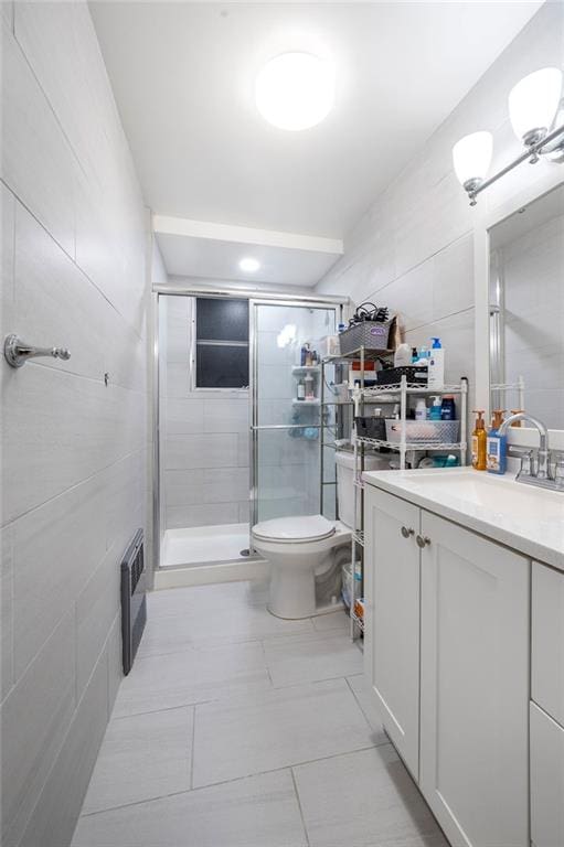 bathroom with a stall shower, toilet, tile walls, and vanity