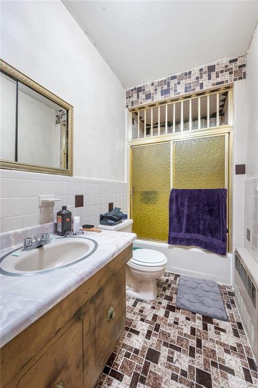 full bathroom featuring tile walls, radiator heating unit, toilet, vanity, and shower / tub combination