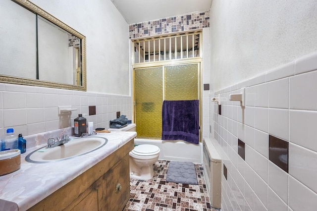 full bath with bathtub / shower combination, toilet, vanity, tile walls, and wainscoting