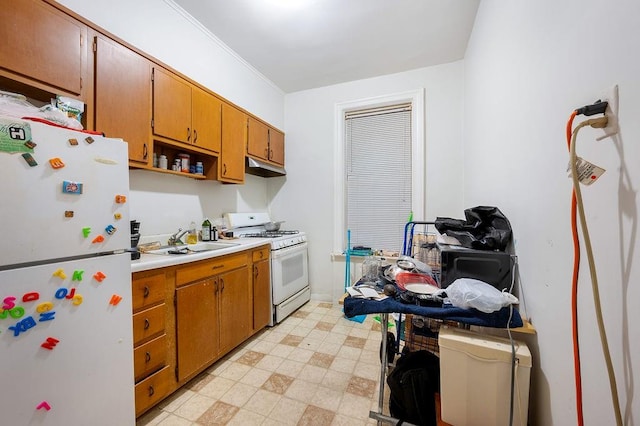 kitchen featuring white appliances, light floors, light countertops, under cabinet range hood, and a sink