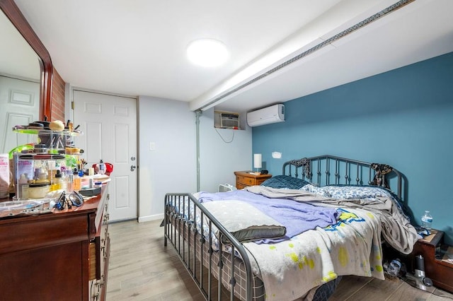 bedroom with wood finished floors and a wall mounted air conditioner