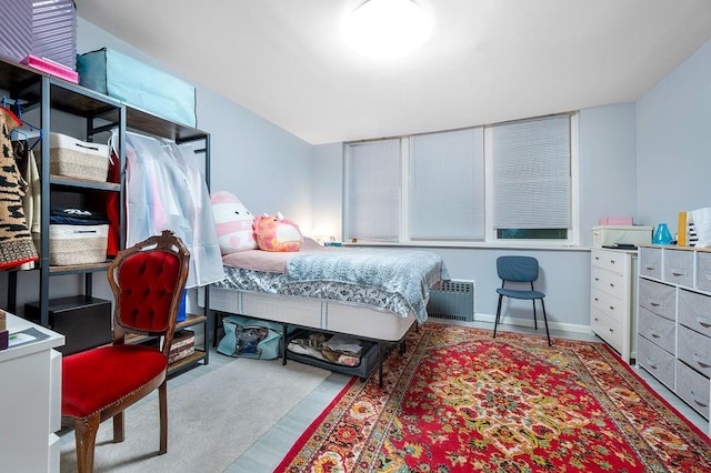 bedroom featuring baseboards, radiator heating unit, and wood finished floors