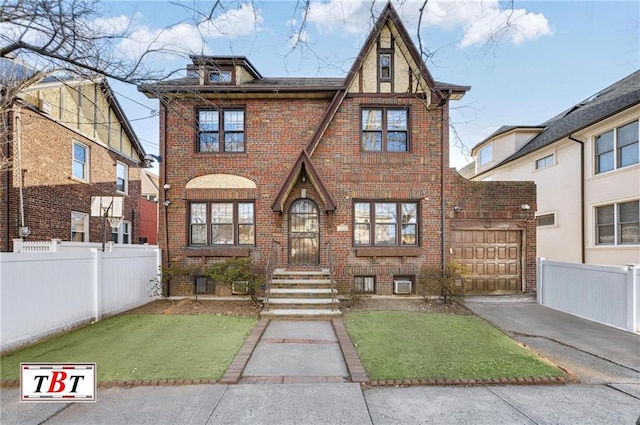 tudor home with driveway, brick siding, and fence