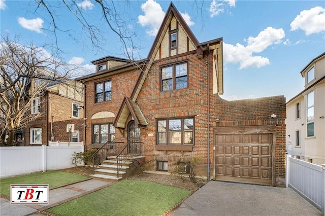 tudor-style house with brick siding, driveway, and fence