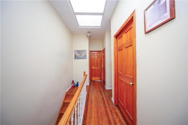 corridor with baseboards, wood finished floors, and an upstairs landing