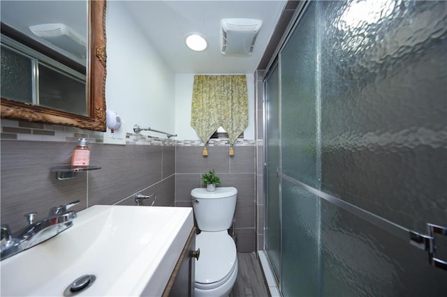 bathroom with tile walls, a shower stall, toilet, and vanity