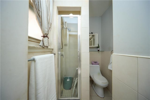 bathroom with a stall shower, tile walls, and toilet