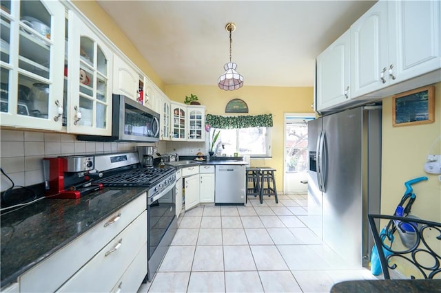 kitchen with glass insert cabinets, light tile patterned floors, appliances with stainless steel finishes, and decorative backsplash