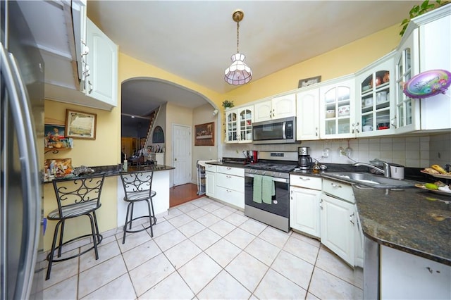 kitchen with tasteful backsplash, appliances with stainless steel finishes, white cabinetry, pendant lighting, and a sink